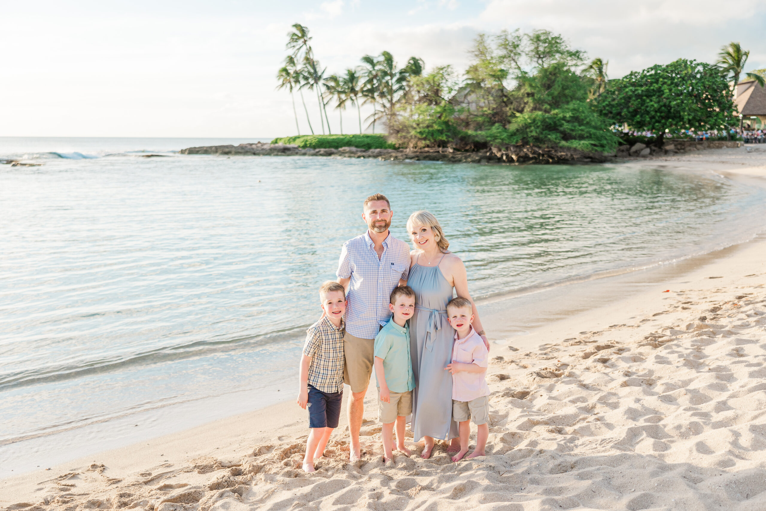 family of 5 standing in a lagoon on oahu surrounded by sand and teal waters