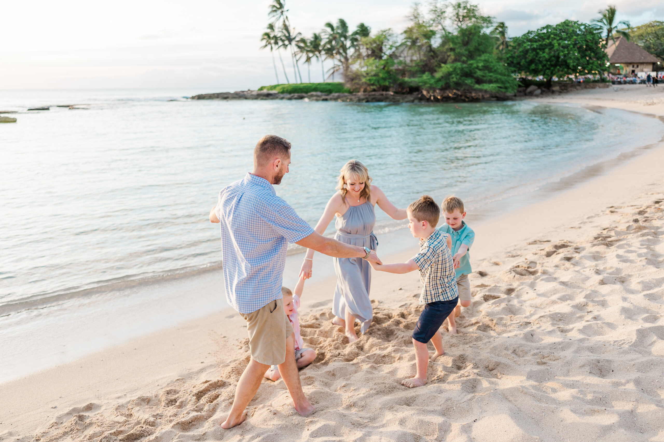 a family of 5 doing "ring around the rosie" during their Aulani Mini Session
