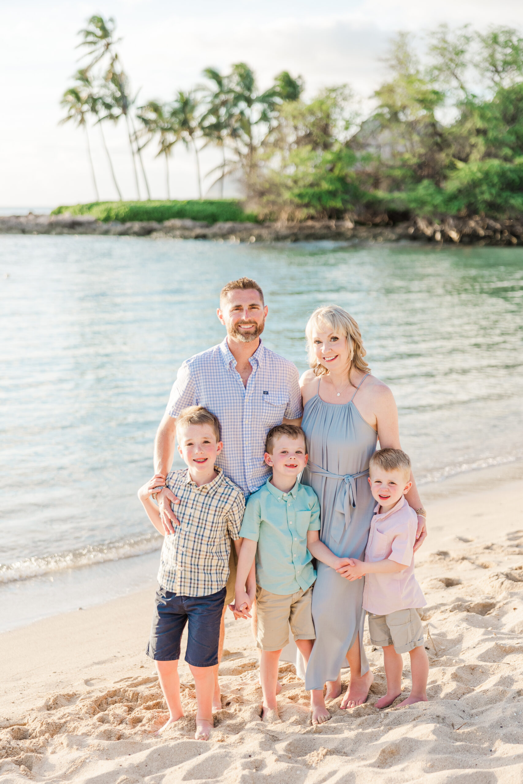 Family of five smiling at the camera standing in a lagoon during their Aulani Mini Session